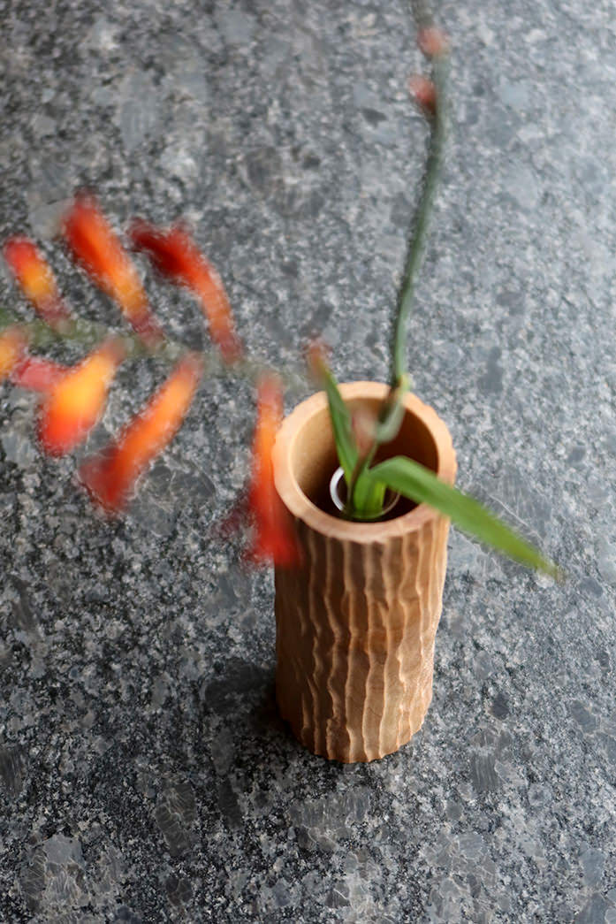 Trævase med reagensglas og blomst